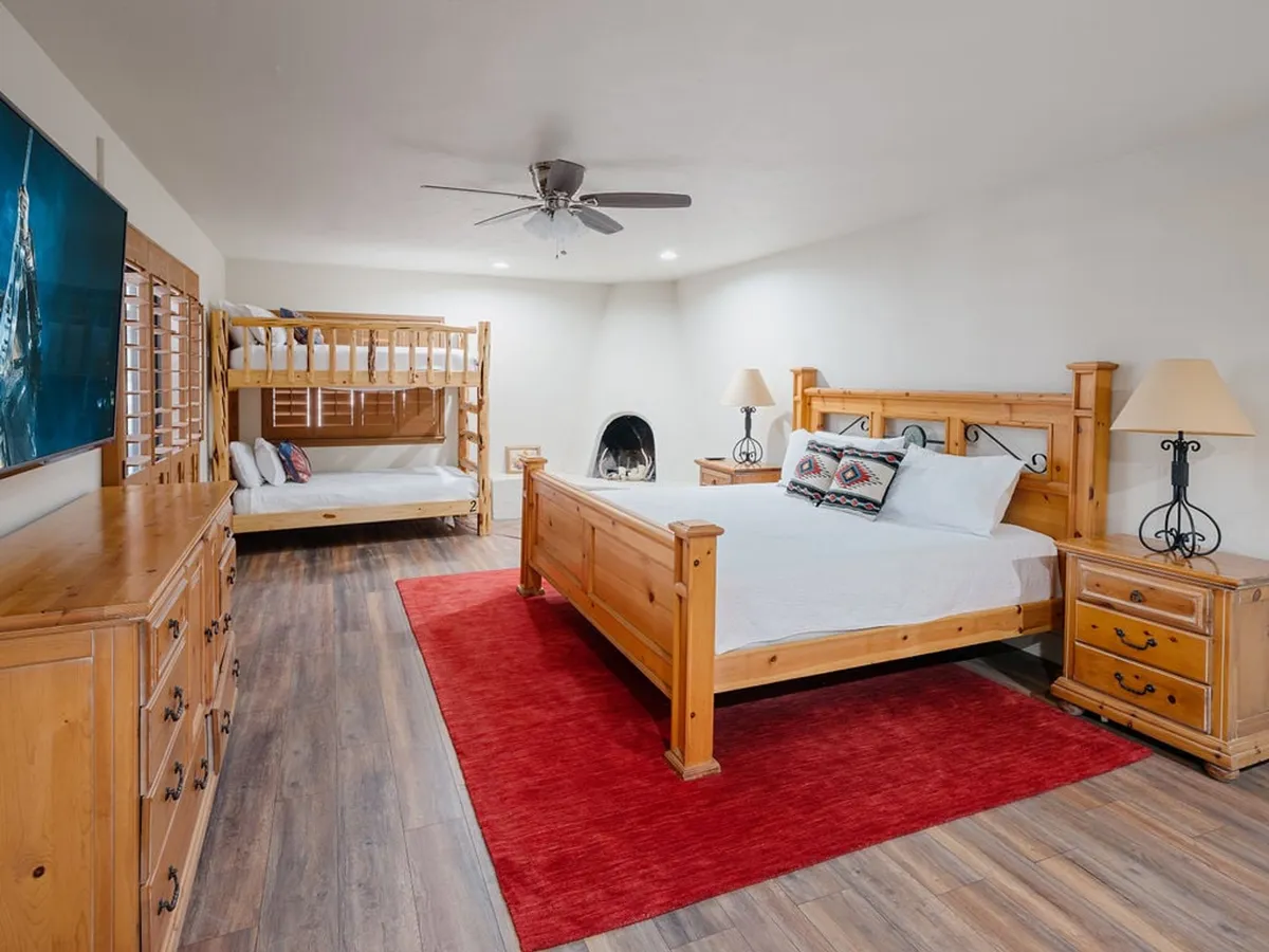 A spacious, family-friendly bedroom with a large wooden bed, bunk bed, fireplace, and a TV. The layout accommodates multiple guests and provides amenities for both adults and children, echoing the multi-family and pet-friendly features described.